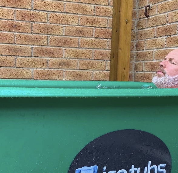 man sitting in an recoverystore Ice bath in the back garden