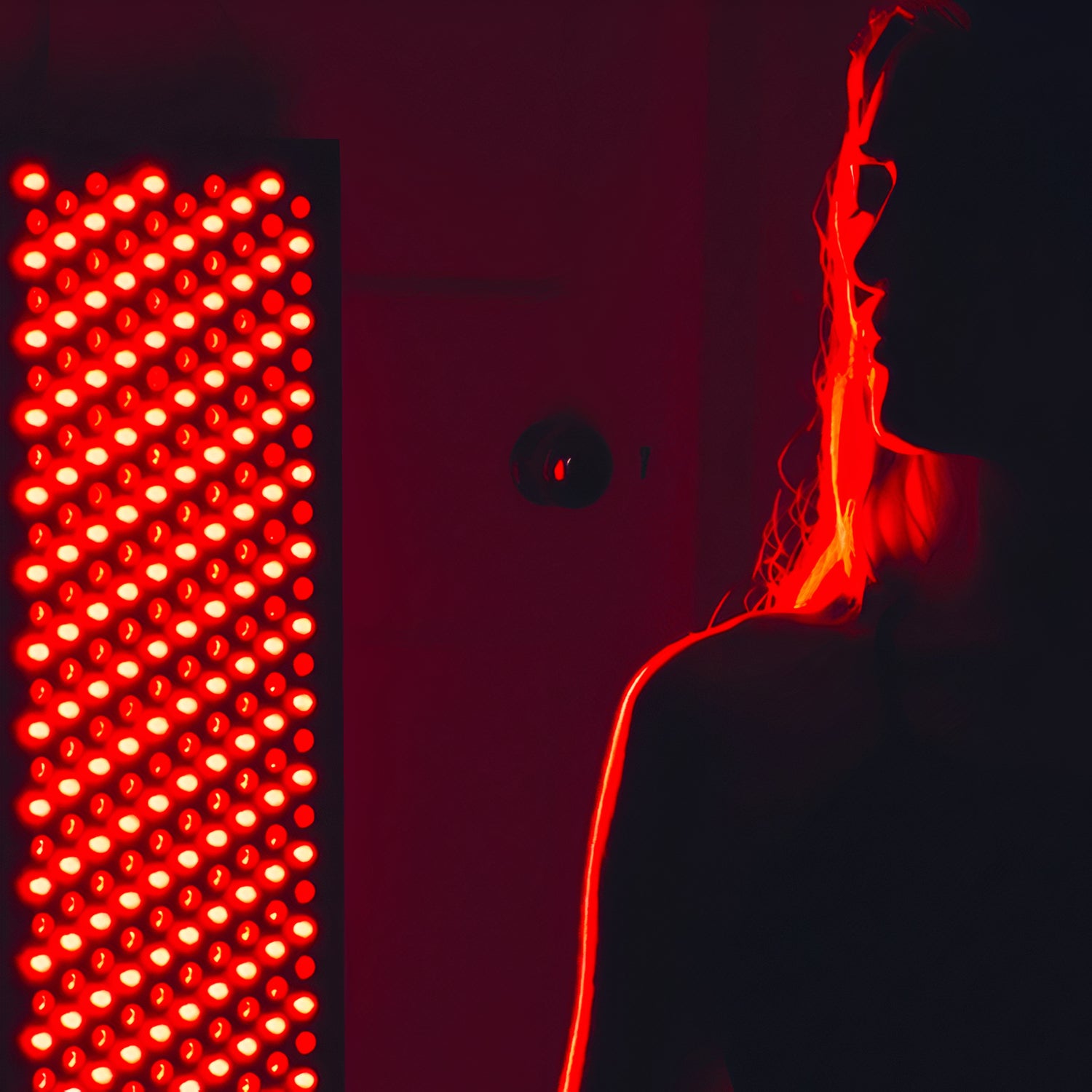 girl with her back against a red light therapy panel