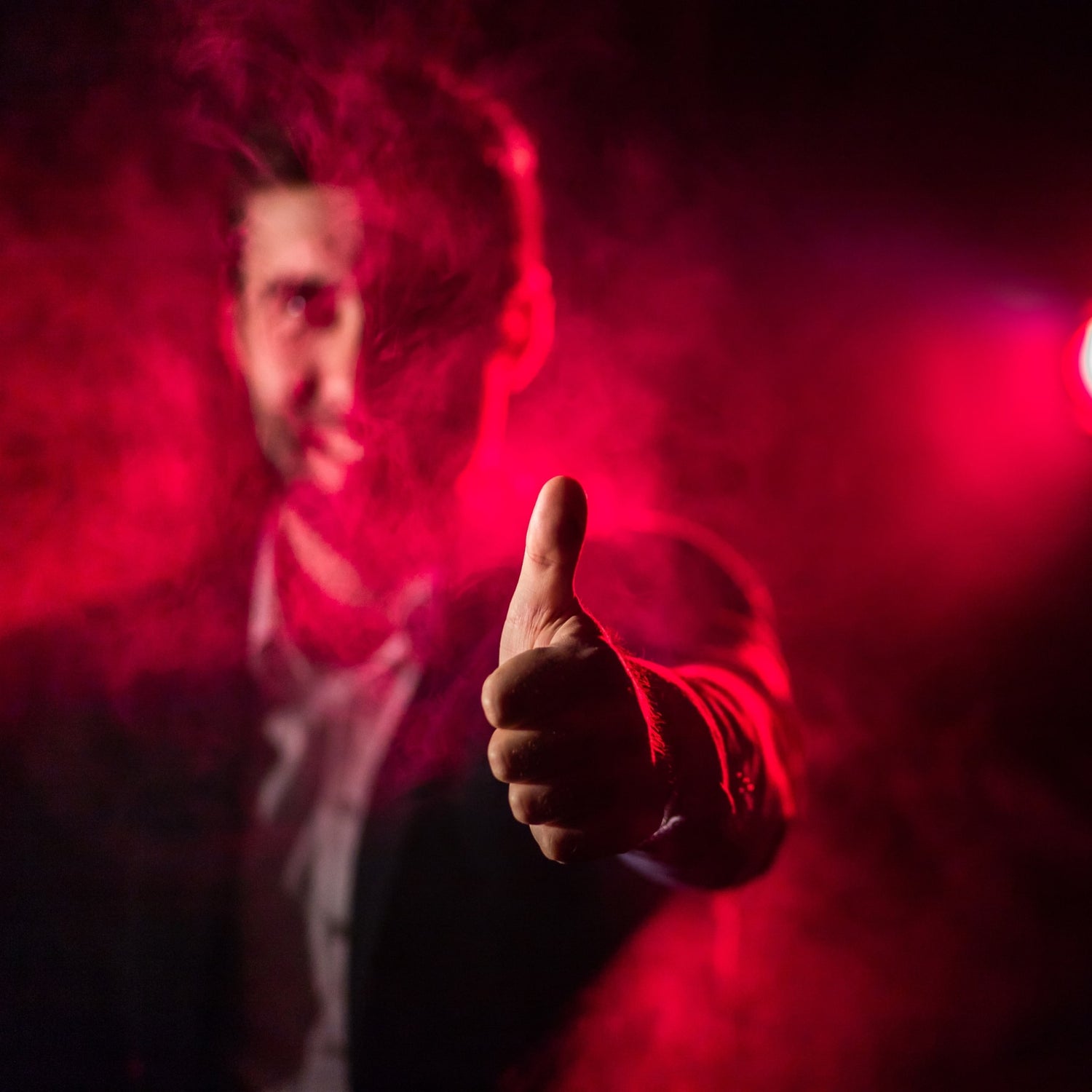 man with his thumb up with smoke around him
