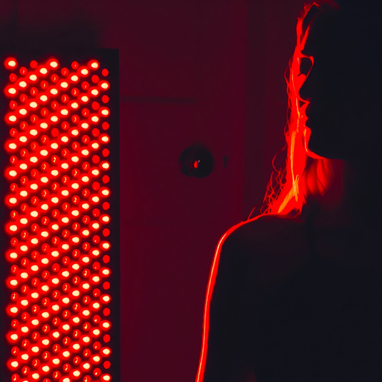 girl with her back against a red light therapy panel