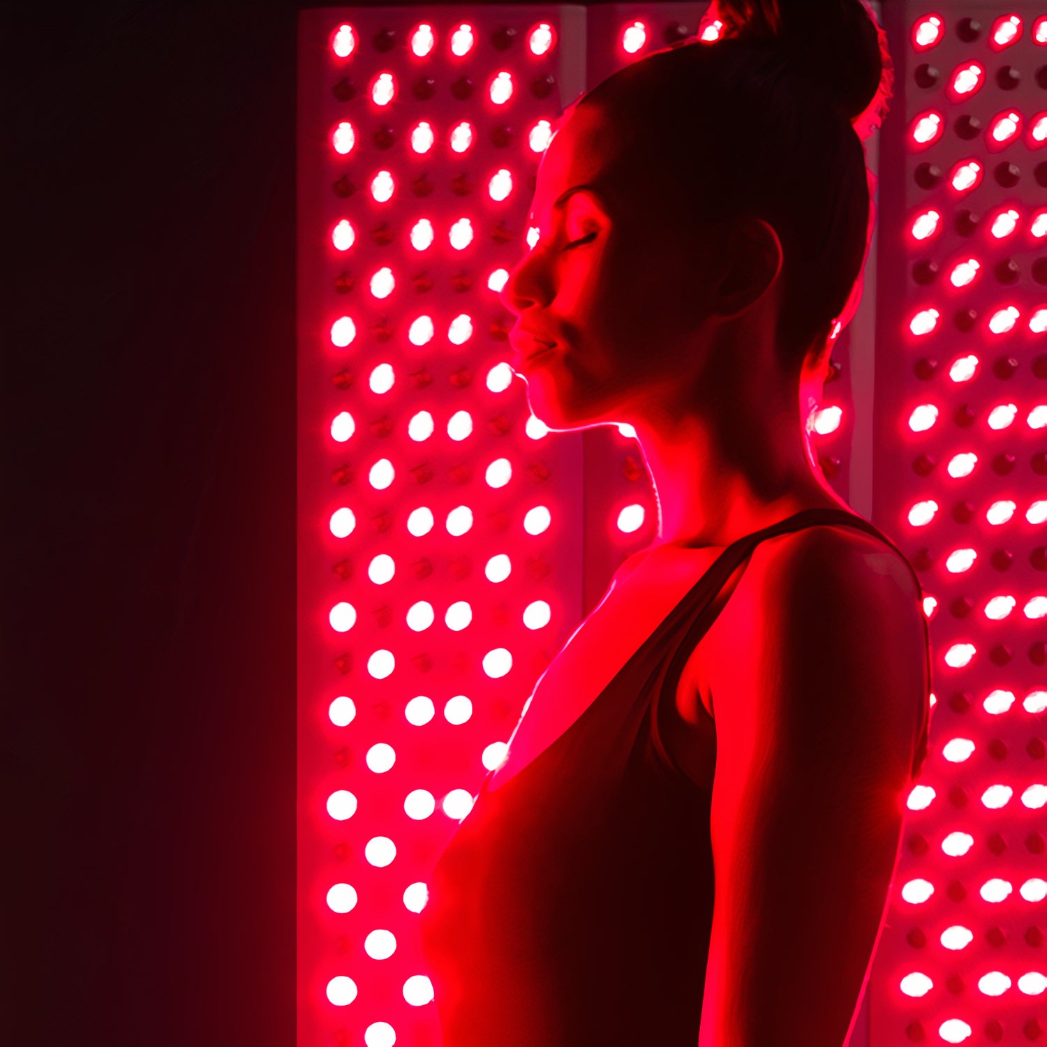 a girl relaxing and being mindful whilst standing in front of two full body red light panels