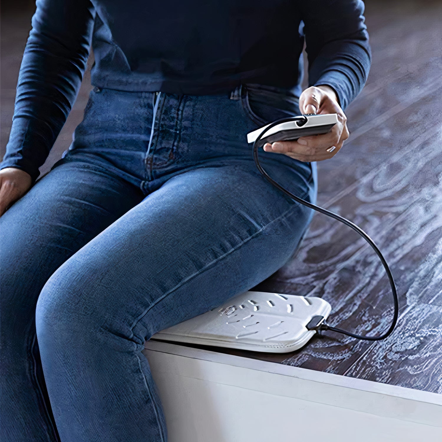 girl with a pulsepad pemf machine under her leg sitting with jeans onin the uk